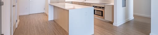 A kitchen with a white island and wooden floors.