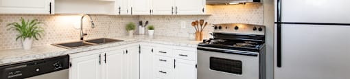 A modern kitchen with white cabinets and stainless steel appliances.