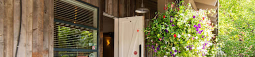 Front door of a wooden building with flowers in front of it at Mullan Reserve Apartments in Missoula, MT