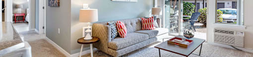 Living room with light blue walls, gray couch, and coffee table at Mullan Reserve Apartments in Missoula, MT