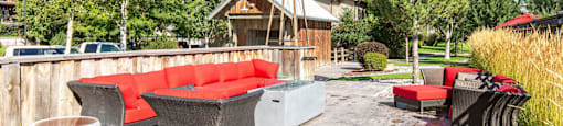 Outdoor seating area with red patio furniture, table, and a fire pit at Mullan Reserve Apartments in Missoula, MT