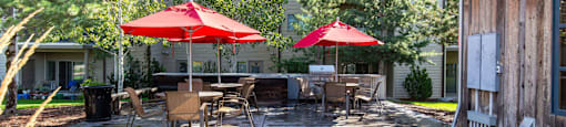 Patio with red umbrellas, tables, and chairs at Mullan Reserve Apartments in Missoula, MT