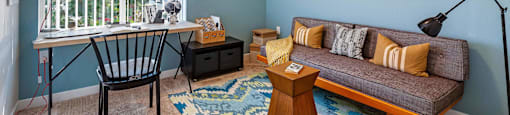 A room with light blue walls, a couch, and a desk with a chair at Mullan Reserve Apartments