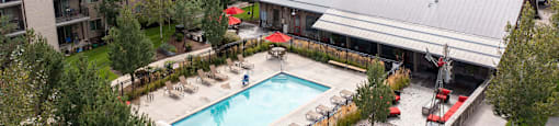 Aerial view of the resort style pool with lounge chairs and umbrellas at Mullan Reserve Apartments in Missoula, MT