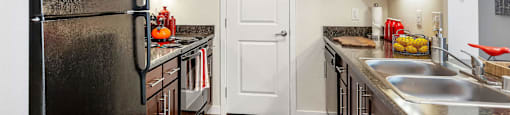 Kitchen with dark wood cabinets, black appliances at Mullan Reserve Apartments in Missoula, MT