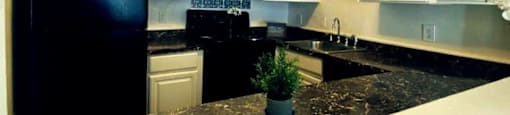 A black fridge and white cabinets in a kitchen.at Ridgewood Apartments, Greensboro, NC 27410