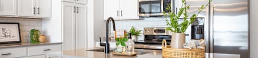 A kitchen with white cabinets and a stainless steel refrigerator.