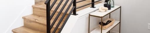 A staircase with a black railing and a round black object on the wall.