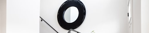 A staircase with a black railing and a round mirror above it.