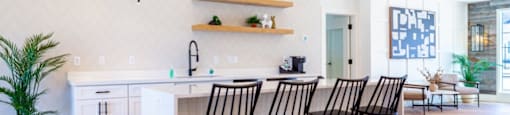 A kitchen with a white counter and black chairs.