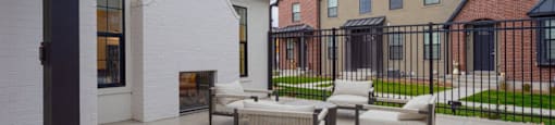 A patio with a table and chairs is in front of a brick building.