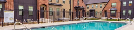 A swimming pool in front of a row of houses.