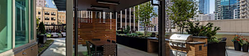 a rooftop patio with a grill and a dining area with a city in the background