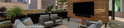 a terrace with a couch and chairs and a television