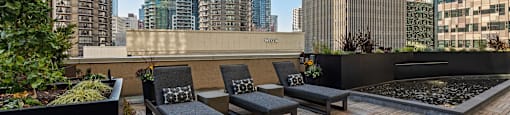 a rooftop deck with lounge chairs and a fountain and skyscrapers in the background