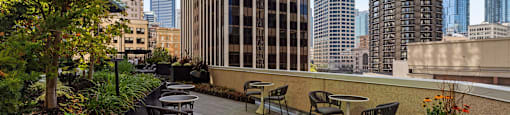 a rooftop patio with tables and chairs and a view of the city