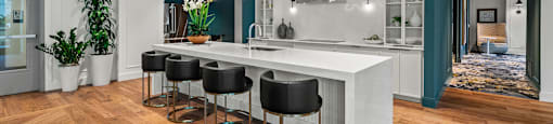 a kitchen with a large white island and black stools