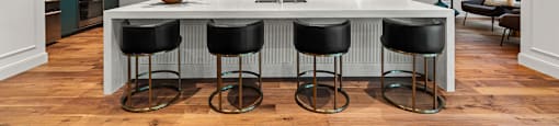 a kitchen with a large island with four black stools