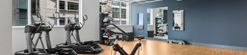 a gym with treadmills and other exercise equipment on a wooden floor