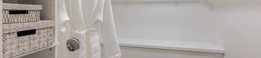 a walk in closet with a white robe and shelves