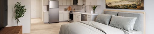 a bedroom with a bed and a kitchen in a room