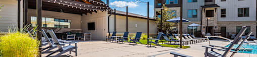 A sunny day at the poolside with lounge chairs and a building in the background.