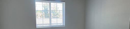 A room with a window and a heater on the floor.