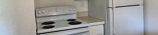 A white kitchen with a stove, oven, and refrigerator.