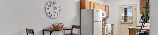 A kitchen with a table and chairs and a clock on the wall.