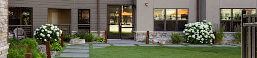 an exterior view of an apartment building with a green lawn and sidewalk at Avenue C Apartments, Billings