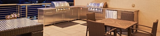 a terrace with tables and chairs and barbecue grill and outdoor lighting at Avenue C Apartments, Montana