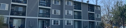 a grey apartment building with a green lawn in front of it