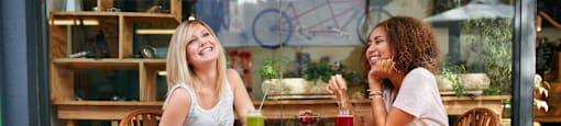 Two women sitting at a table outside a cafe.