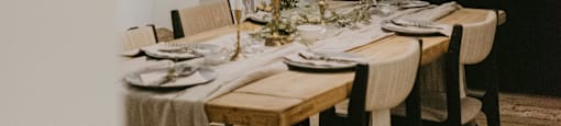 A dining table set for a meal with chairs around it.
