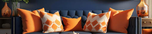 A living room with a blue couch and orange pillows.