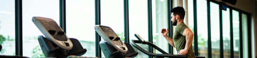A man is running on a treadmill in a gym.