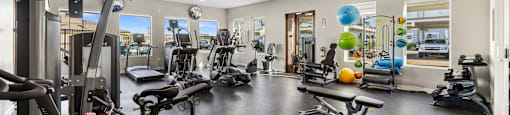 a gym with weights and other exercise equipments in a room with windows