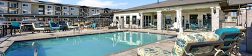 a swimming pool with lounge chairs next to a building