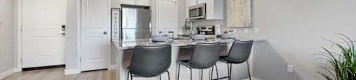 a kitchen with a bar with three chairs