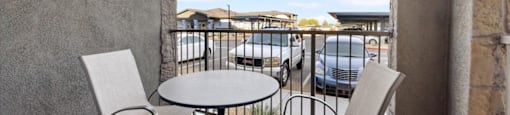 a balcony with a table and two chairs and a view of a pool