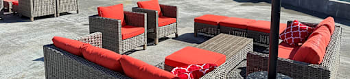 an outdoor patio with orange chairs and a fire pit in front of an apartment building