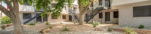 a courtyard with trees in front of a building