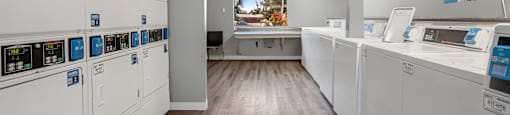 a laundry room with washes and dryers and a counter with a window