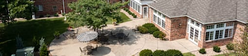 A large house with a red brick exterior and a circular patio with a table and chairs.