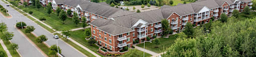 an aerial view of a large apartment complex with a green field in the background