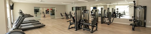 a gym with cardio equipment and weights on a wooden floor