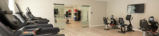 a gym filled with cardio machines and a tv
