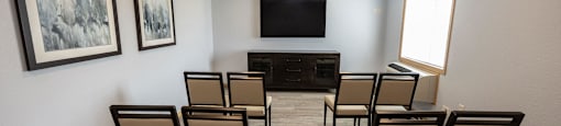 a small conference room with chairs and a tv on the wall