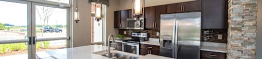 a kitchen with a large island and a stainless steel refrigerator