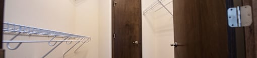 a walk in closet with a wooden door and a hanging rack